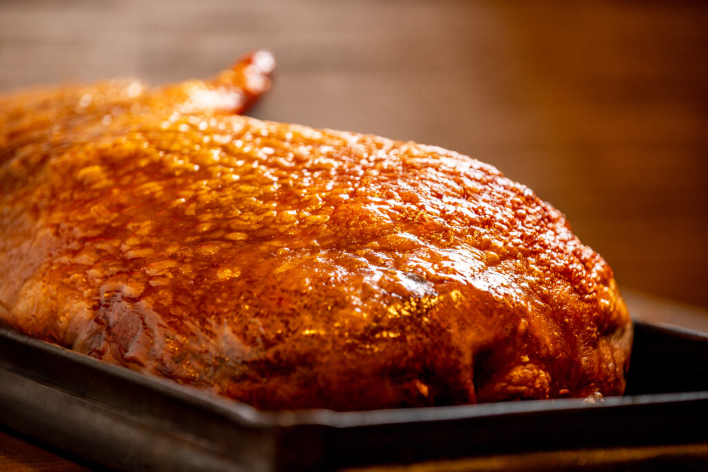 Variedad de platos gourmet de Le Pork presentados en platos negros sobre mesa elegante: chicharrón carnudo, mazorcada, costillas y arepachona.